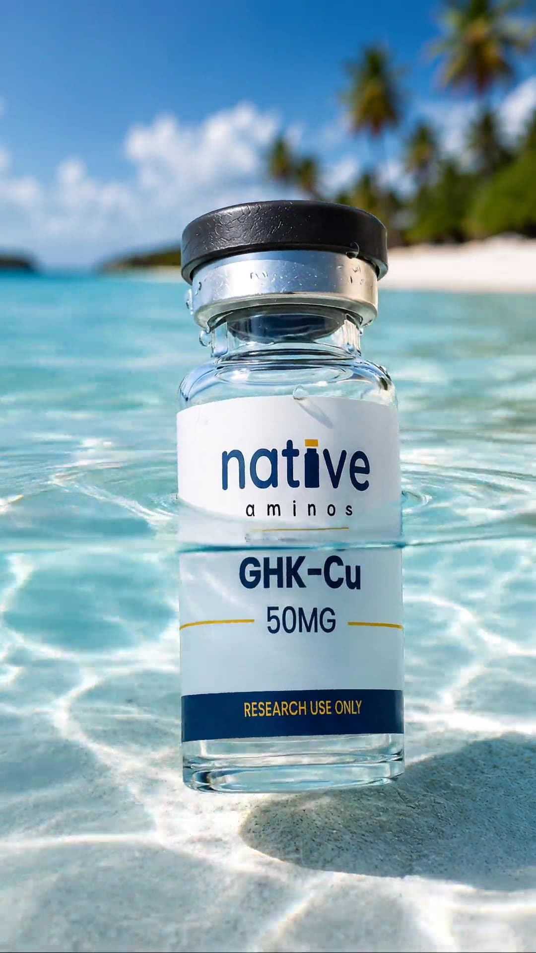 A Native Aminos GHK-Cu vial standing in shallow water on white sand.